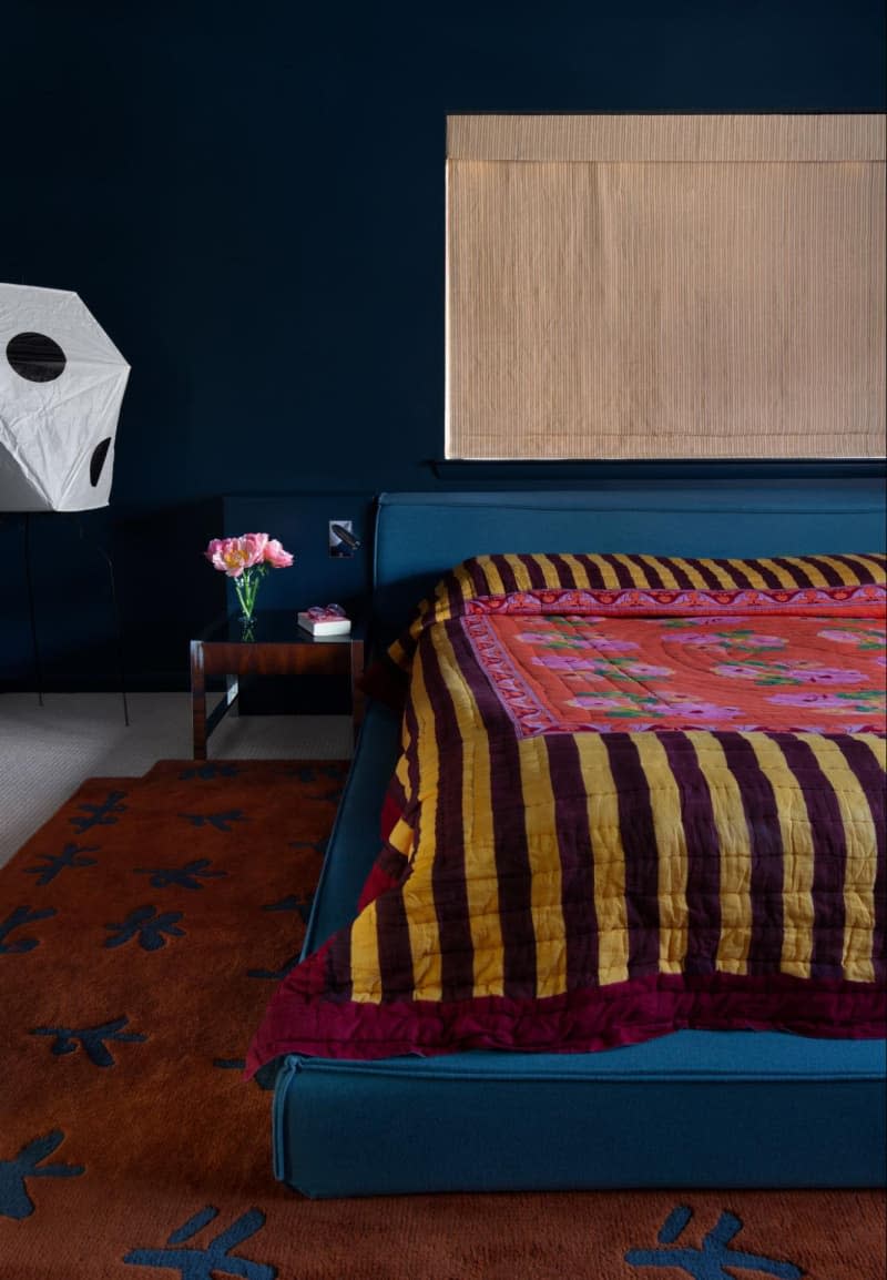 Bedroom with deep dramatic colors and textiles with stripes, florals