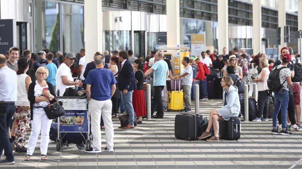 People wait outside the Munich Airport in Munich, Germany, Tuesday, Aug. 27, 2019. Munich Airport says it has closed some of its terminals because a person has likely entered the "clean area" through an emergency exit door. The international airport tweeted Tuesday morning that terminal 2 and areas B and C or terminal 1 had been closed for police operations.(AP Photo/Matthias Schrader)