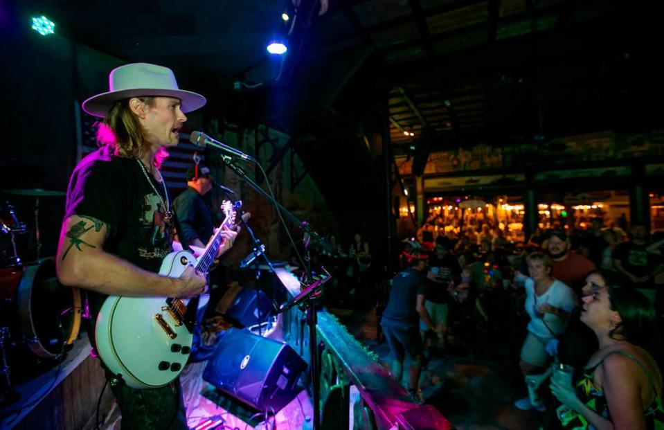 La gente baila mientras David Bryce Warren, a la izquierda, actúa con la banda Cayo Hueso Riot en The Bull en Cayo Hueso, Florida, el sábado 11 de diciembre de 2021.