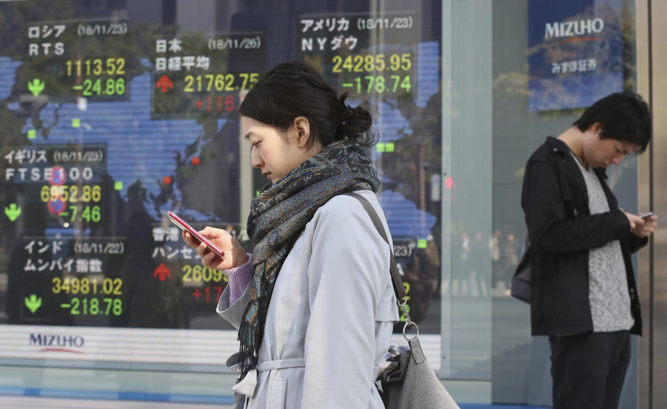 People look at their cell-phone in front of an electronic stock board of a securities firm in Tokyo, Monday, Nov. 26, 2018. Asian shares were mostly higher Monday on hopes that U.S. President Donald Trump and his Chinese counterpart Xi Jinping will unwind a blistering trade dispute at a meeting this week. (AP Photo/Koji Sasahara)