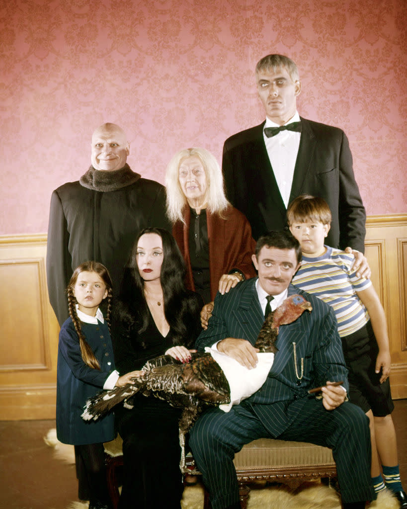 The image features characters Uncle Fester, Grandmama, Lurch, Wednesday, Morticia, Gomez, and Pugsley from "The Addams Family" TV show, posing with a turkey