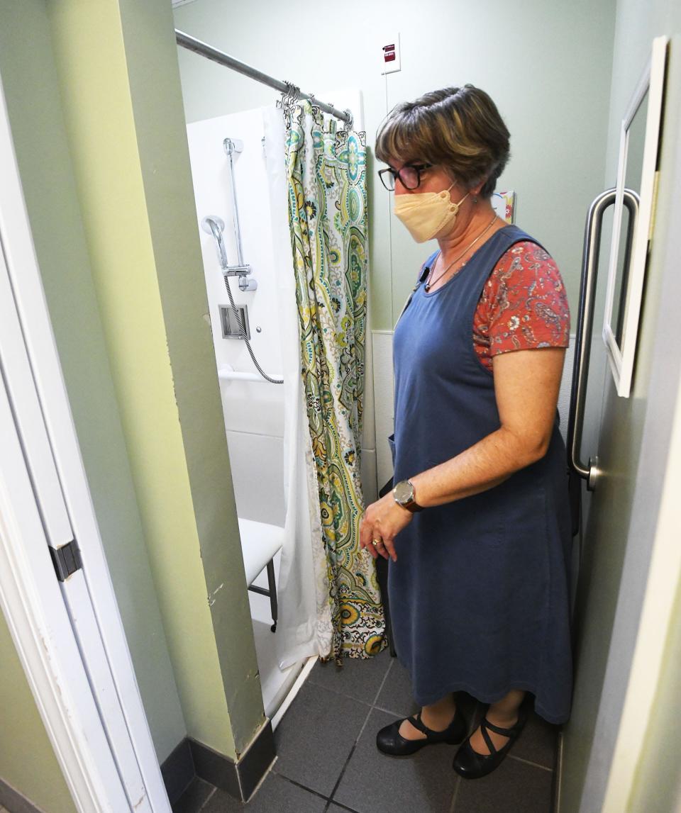 Rosemary Kamireddy, a clinical community liaison for United Community & Family Services, shows a shower in a bathroom at Sheltering Arms that will be renovated tied to an announcement that the 1926 assisted living building in Norwich will undergo $4.5 million in renovations.
