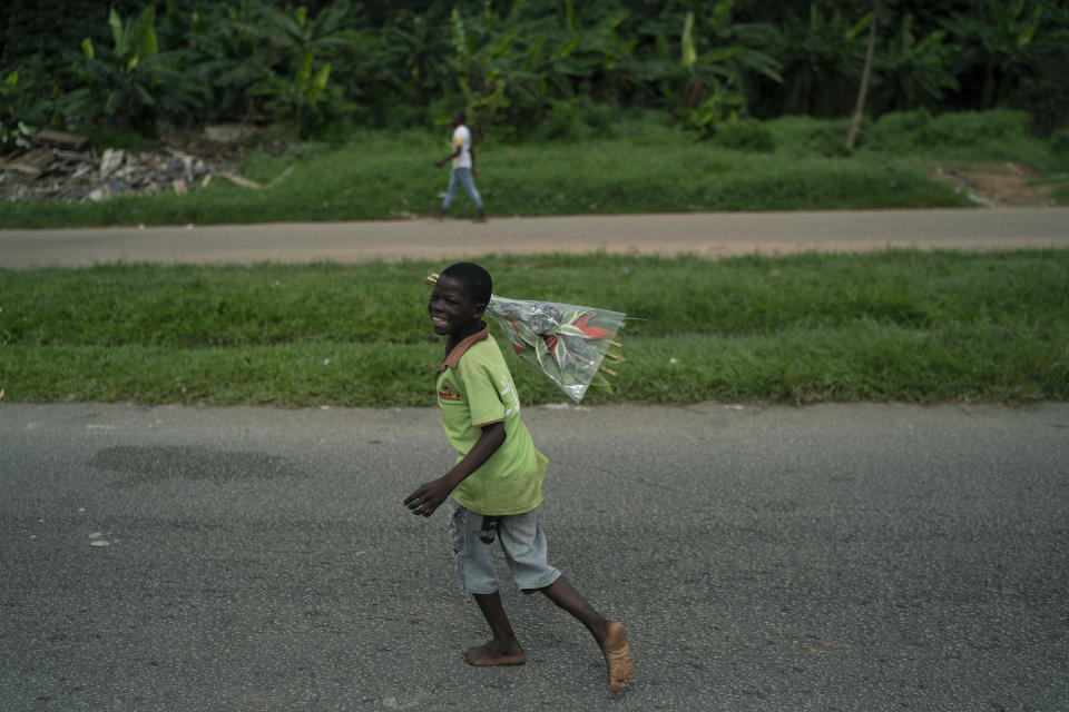 A child holds up a bouquet of flowers to sell as he waits for a customer, at the entrance of a cemetery during the Day of the Dead celebrations in Abidjan, Ivory Coast, Monday, Nov. 2, 2020. International election observers say voter turnout was “extremely low” in parts of Ivory Coast after the leading opposition candidates called for a boycott of the vote. The main opposition parties called on their supporters to stay home to protest President Alassane Ouattara’s bid for a third term. (AP Photo/Leo Correa)