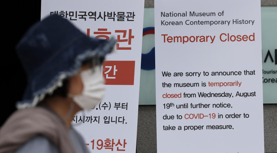 A woman weaning a face mask walks near the notice showing a temporarily closed as a precautions against the coronavirus outside of the National Museum of Korean Contemporary History in Seoul, South Korea, Tuesday, Sept. 1, 2020. South Korea reported more than 200 new cases, mostly from the greater capital area, where officials have restricted dining at restaurants and shut down churches, nightspots, fitness centers and after-school academies to fight a viral resurgence. (AP Photo/Lee Jin-man)