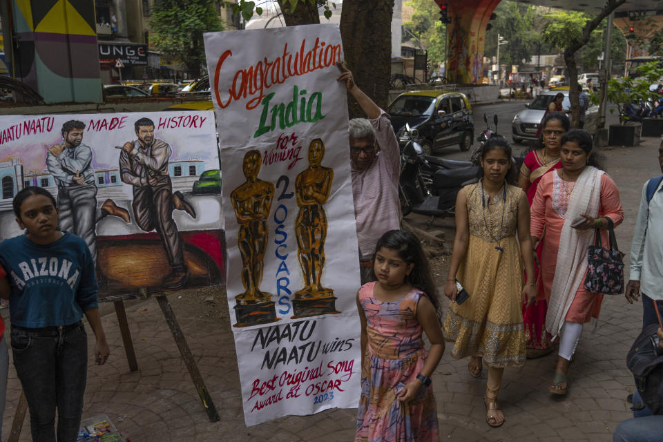 Personas caminan junto a pinturas realizadas para celebrar los dos premios Oscar de India en Bombay. India, el lunes 13 de marzo de 2023. India ganó Premios de la Academia por la canción original "Naatu Naatu" y por el cortometraje documental "The Elephant Whisperers". (Foto AP/Rafiq Maqbool)