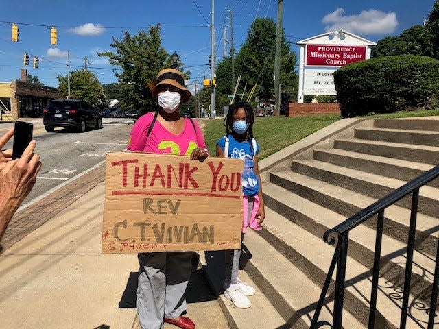 As her granddaughter looks on, Edna Davis, 65, holds up a sign thanking civil rights activist C.T. Vivian outside Vivian's funeral in Providence Missionary Baptist Church in Atlanta on July 23.