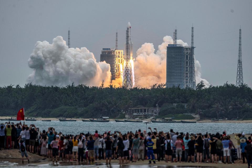 People watch a Long March 5B rocket, carrying China's Tianhe space station core module, as it lifts off.