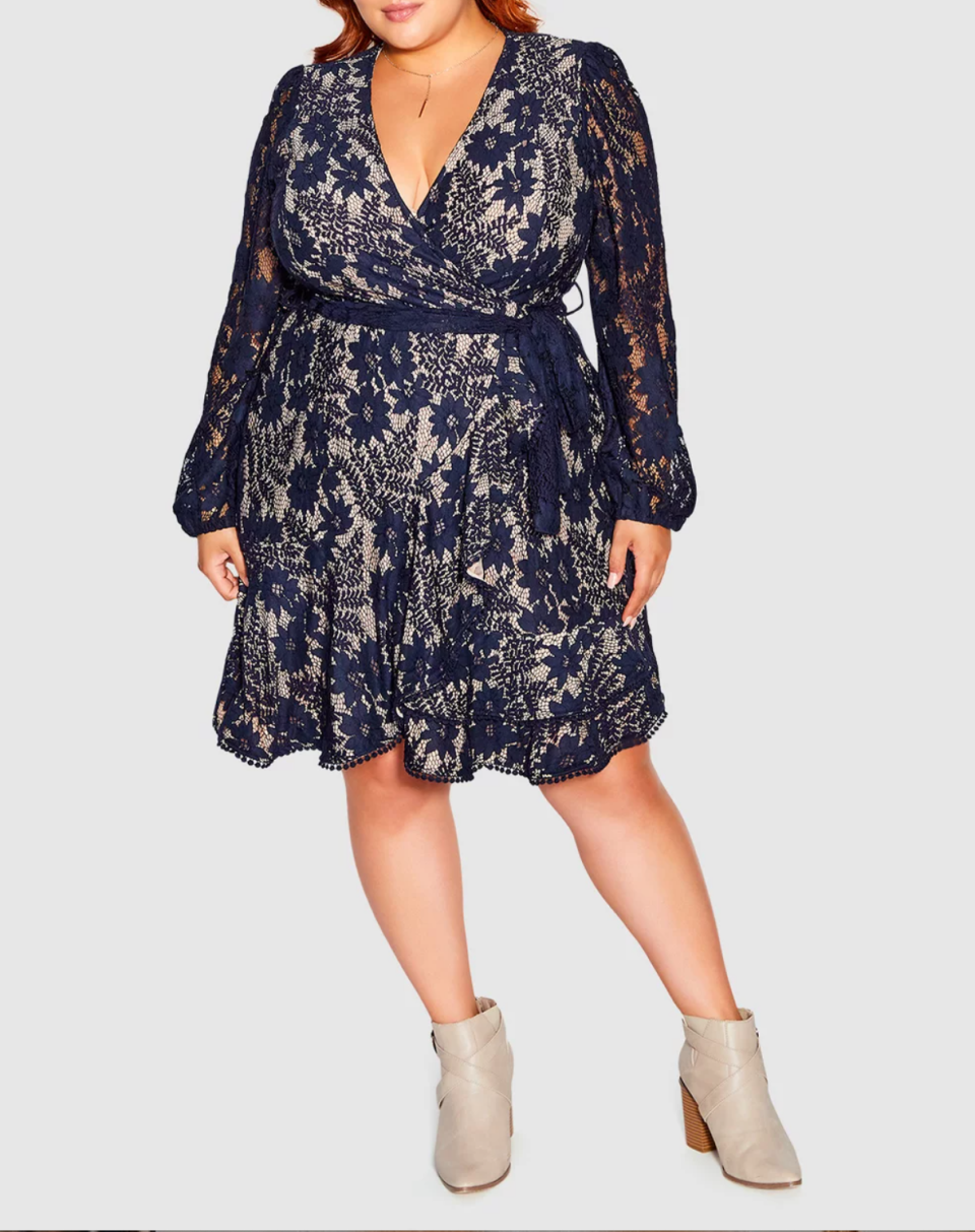 A plus-size model wears a black lace long sleeved knee length dress with beige ankle boots.