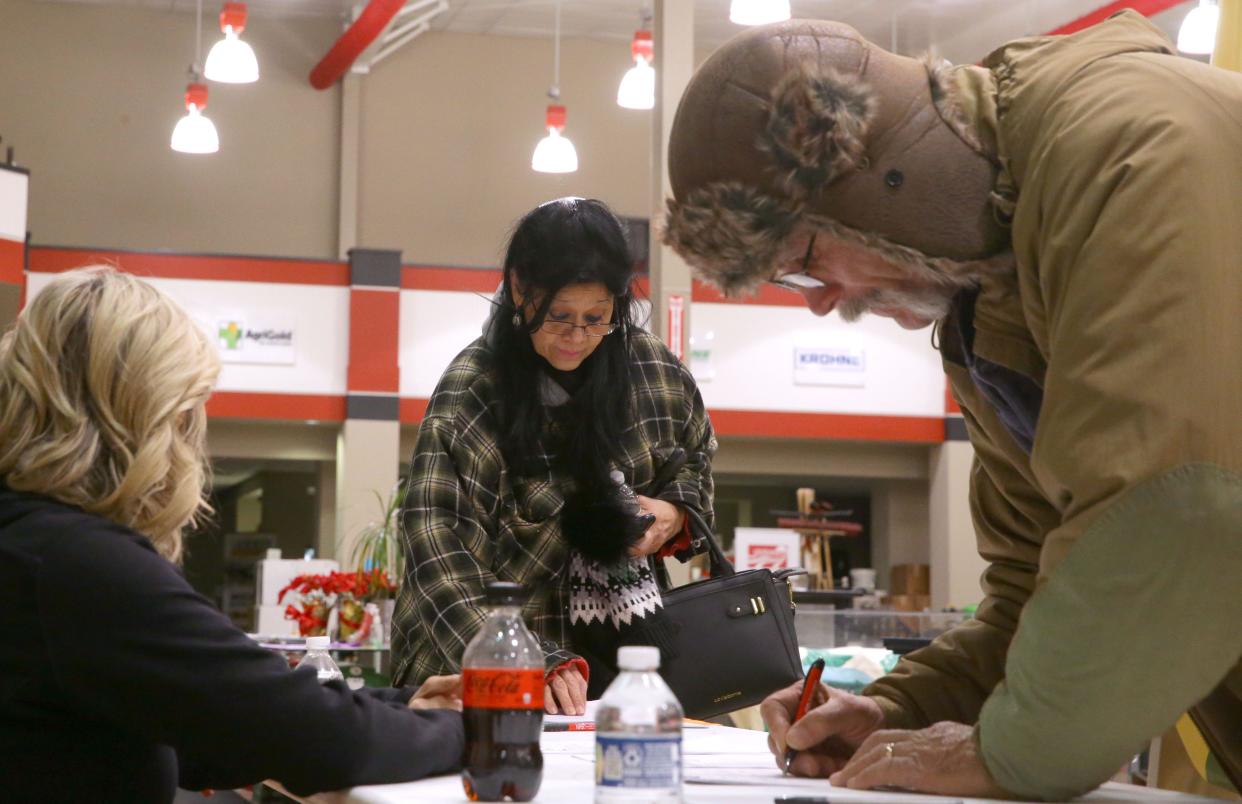 Emy Rivera, center, and Russell Van Horn check in to caucus Monday, Jan. 15, 2024 at Stutsman agricultural products in Hills, Iowa.