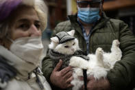 A man wearing a face mask protection to prevent the spread of the coronavirus, holds pet while waiting to be blessing during the feast of St. Anthony, Spain's patron saint of animals, in Pamplona, northern Spain, Sunday, Jan. 17, 2021. The feast is celebrated each year in many parts of Spain and people bring their pets to churches to be blessed. (AP Photo/Alvaro Barrientos)