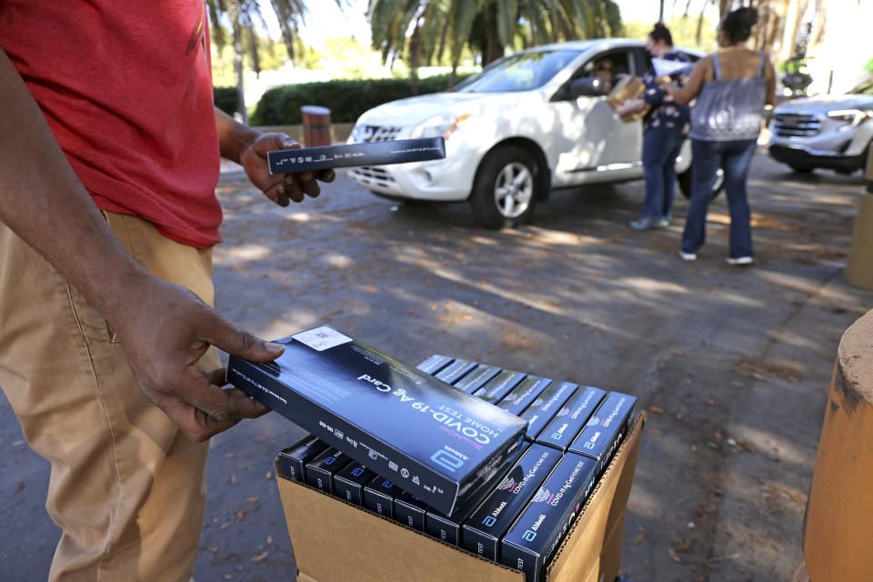 Tramiya Fitzpatrick grabs more COVID-19 at-home rapid test kits to hand out to Broward County residents at the African American Research Library & Cultural Center in Fort Lauderdale, Fla., on Thursday, Dec. 30, 2021. Residents picking up the test kits must show proof of Broward County residency and are limited to two kits per household, while supplies last. (Amy Beth Bennett/South Florida Sun-Sentinel via AP)