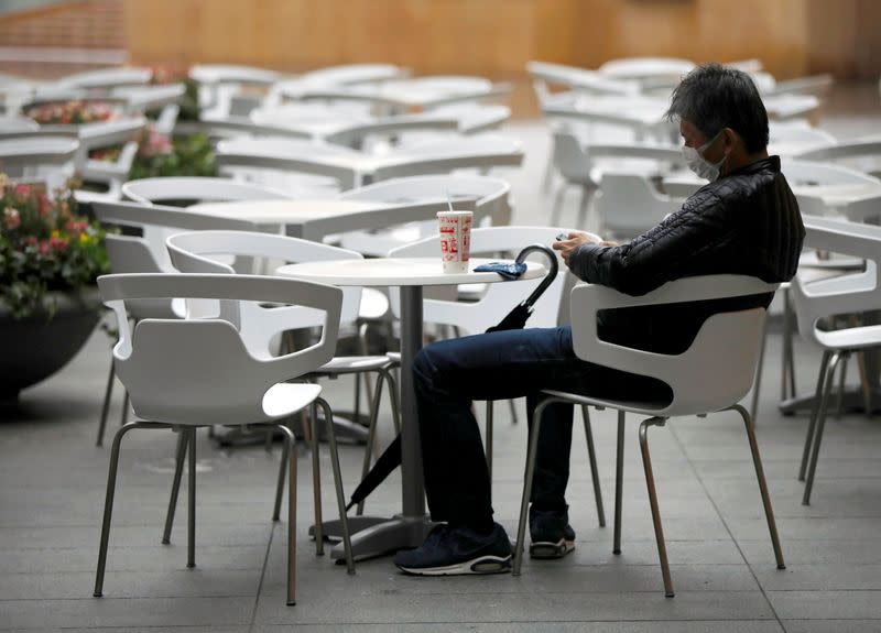 A man wearing a protective face mask, following an outbreak of the coronavirus disease, takes a rest next to empty seats at the Roppongi Hills complex in Tokyo