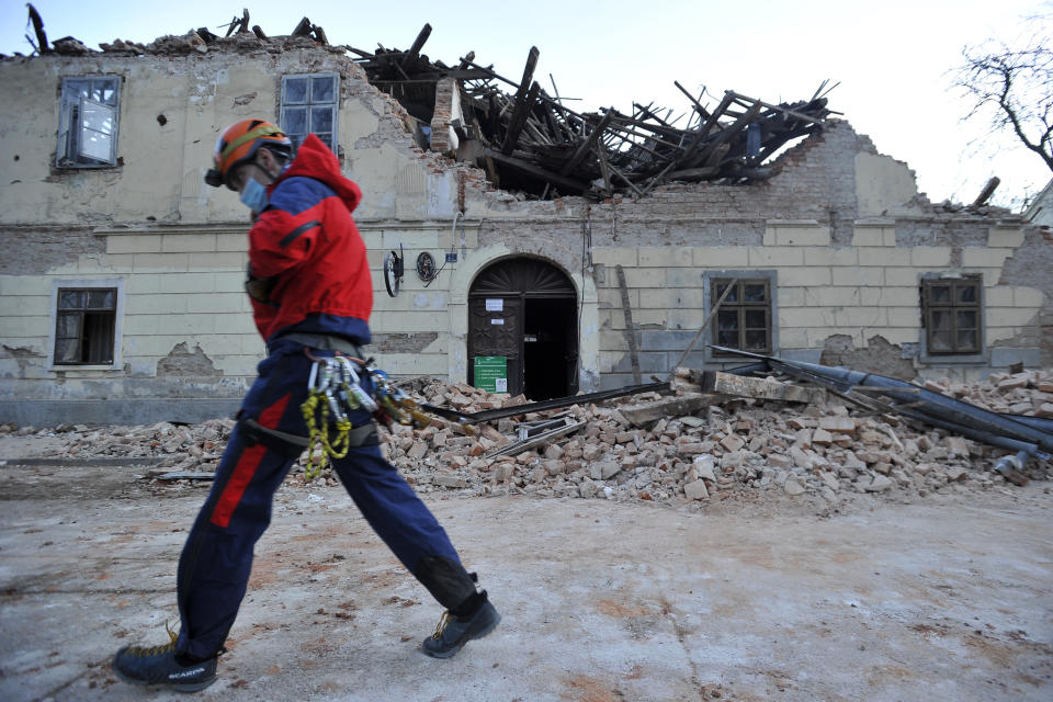 A rescuer walks past a building damaged in an earthquake in Petrinja, Croatia, Tuesday, Dec. 29, 2020. A strong earthquake has hit central Croatia and caused major damage and at least one death and some 20 injuries in the town southeast of the capital Zagreb. (AP Photo)