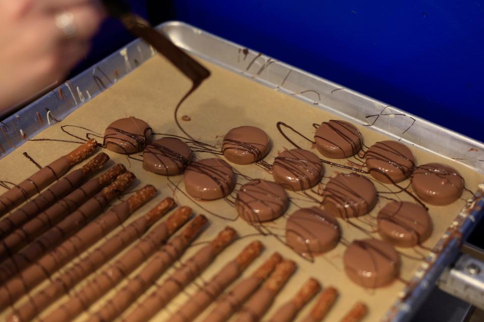 Jenna Raymond puts the finishing touches on Peterbrooke's signature chocolate-dipped cookies and pretzel rods.