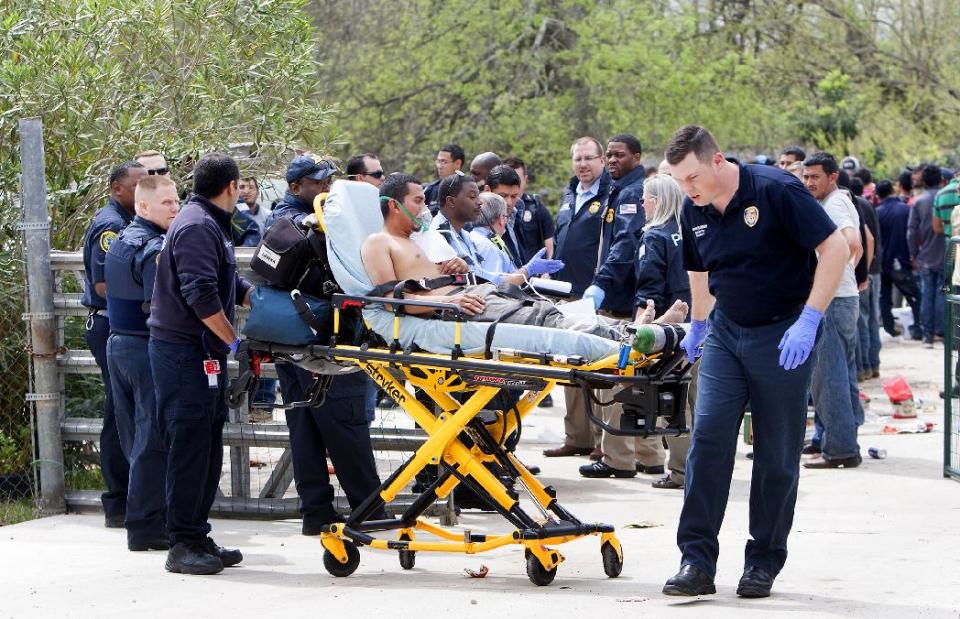 A person is taken from a house on a gurney, Wednesday, March 19, 2014, in southeast Houston. A house overflowing with more than 100 people presumed to be in the United States illegally was uncovered just outside Houston on Wednesday, a police spokesman said. The suspected stash house was found during a search for a 24-year-old woman and her two children that were reported missing by relatives Tuesday after a man failed to meet them, said a spokesman for the Houston Police Department. (AP Photo/Houston Chronicle, Cody Duty)