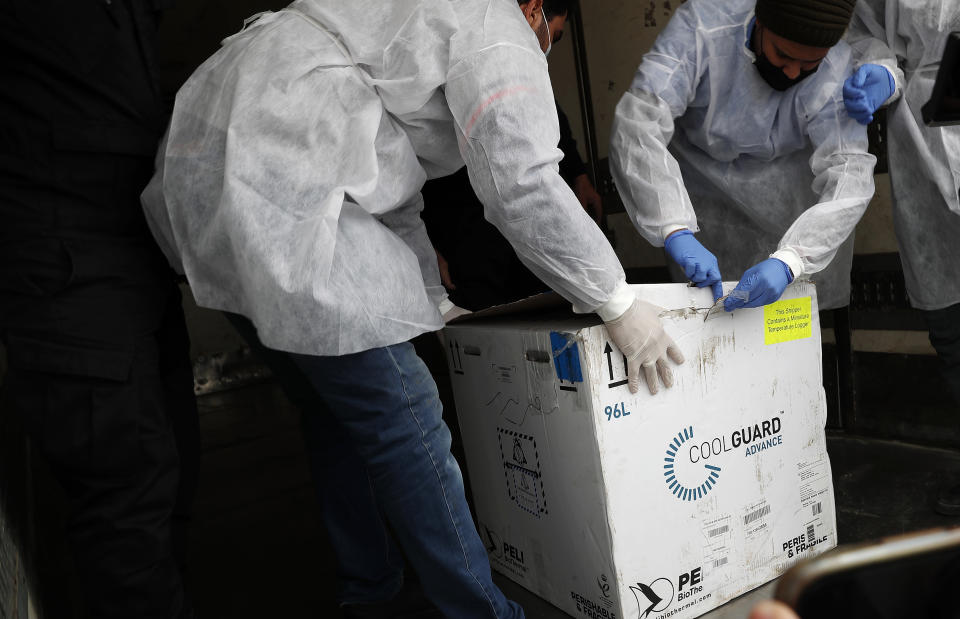 Medics open a box of the Russian Sputnik V coronavirus vaccines inside a truck at the Kerem Shalom border crossing, in Rafah, Gaza Strip, Wednesday, Feb. 17, 2021. The Palestinian Authority said Wednesday that it dispatched the first shipment of coronavirus vaccines to the Hamas-ruled Gaza Strip, two days after accusing Israel of preventing it from sending the doses amid objections from some Israeli lawmakers. (AP Photo/Adel Hana)