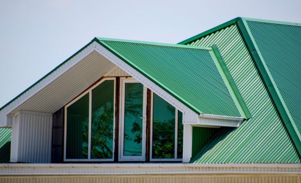 view of top floor of large house with green metal roof with windows into attic space