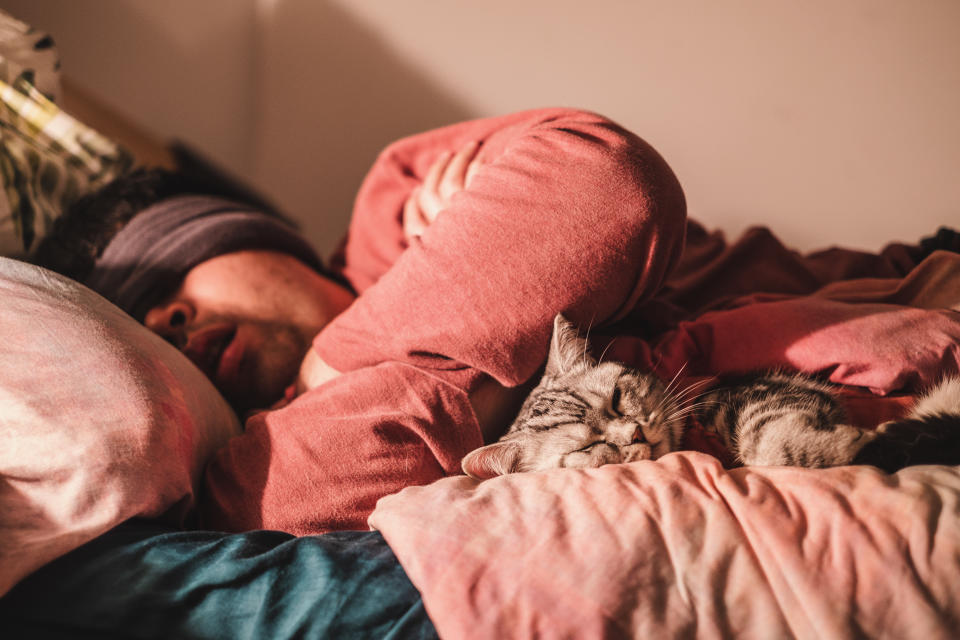 asian man wearing sleep mask, sleeping with his cat