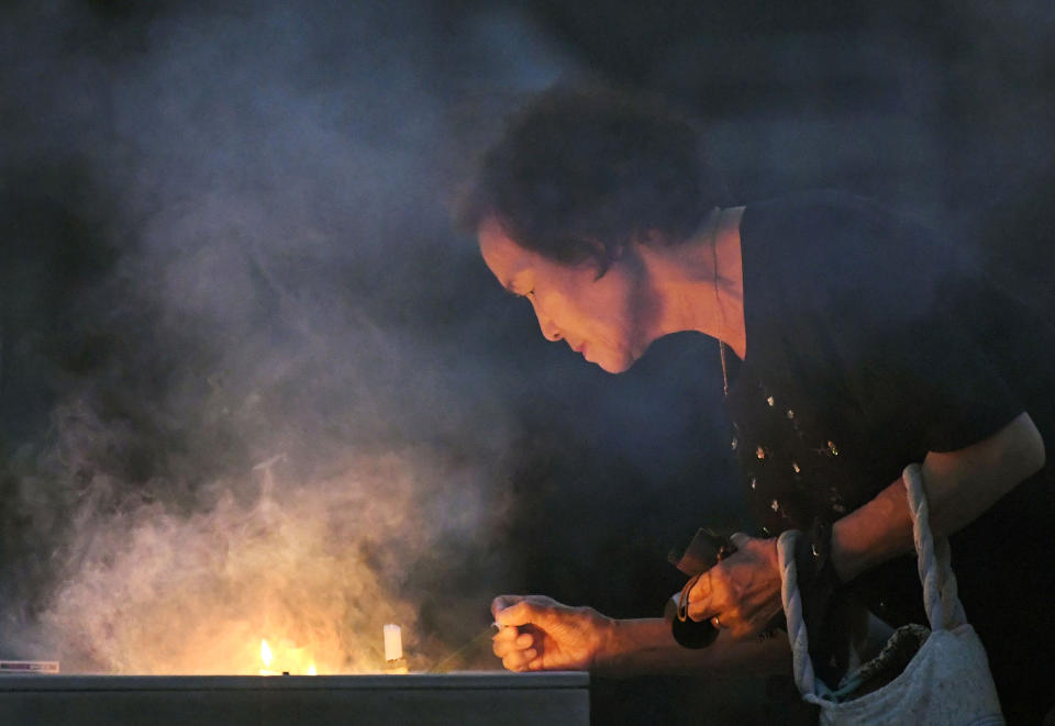 A woman burns a stick of incense at the cenotaph dedicated to the victims of atomic bombing at Hiroshima Peace Memorial Park in Hiroshima, western Japan, Monday, Aug. 6, 2018, marking the 73rd anniversary of the bombing. (Yohei Nishimura/Kyodo News via AP)