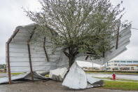 A piece of a building is wrapped around a tree where a tornado was reported to pass along Mickey Gilley Boulevard near Fairmont Parkway, Tuesday, Jan. 24, 2023, in Pasadena, Texas. (Mark Mulligan/Houston Chronicle via AP)