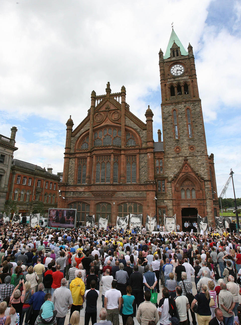 People watch Prime Minister David Cameron’s apology on a giant screen outside the Guild Hall in Derry (Niall Carson/PA)