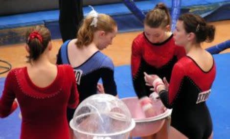 Gymnasts pepare their hands with chalk.