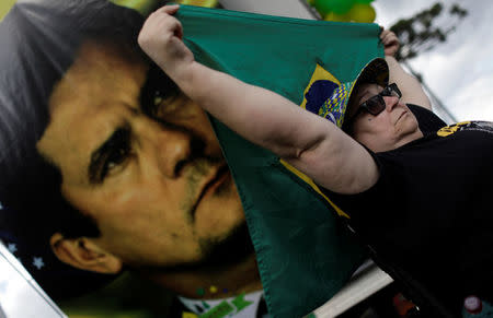 A demonstrator holds a Brazilian National flag next to a picture of the federal Judge Sergio Moro in front of the Federal Police headquarters, where former Brazilian President Luiz Inacio Lula da Silva was sentenced to serve a 12-year prison sentence for corruption, in Curitiba, Brazil April 6, 2018. REUTERS/Ricardo Moraes