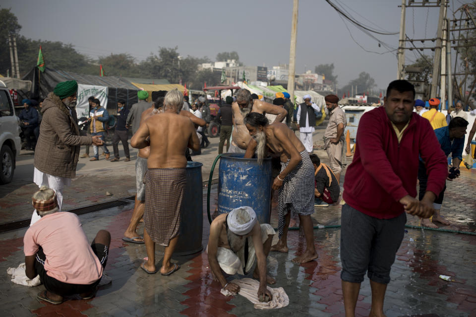 Protesting farmers bathe at a fuel station along a major highway as they block a major highway during a protest to abolish new farming laws they say will result in exploitation by corporations, eventually rendering them landless, at the Delhi-Haryana state border, India, Tuesday, Dec. 1, 2020. The busy, nonstop, arterial highways that connect most northern Indian towns to this city of 29 million people, now beat to the rhythm of never-heard-before cries of "Inquilab Zindabad" ("Long live the revolution"). Tens and thousands of farmers, with colorful distinctive turbans and long, flowing beards, have descended upon its borders where they commandeer wide swathes of roads. (AP Photo/Altaf Qadri)