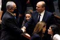 Head of Oposition Benjamin Netanyahu and Israel Prime minister Naftali Bennett shake hands following the vote on the new coalition at the Knesset, Israel's parliament, in Jerusalem