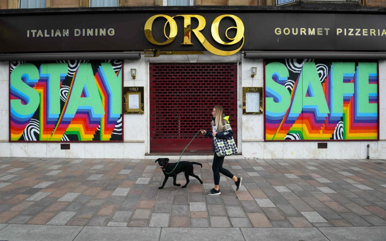 A pedestrian walks past a shuttered restaurant with a mural that reads "Stay Safe" on it in Glasgow - AFP
