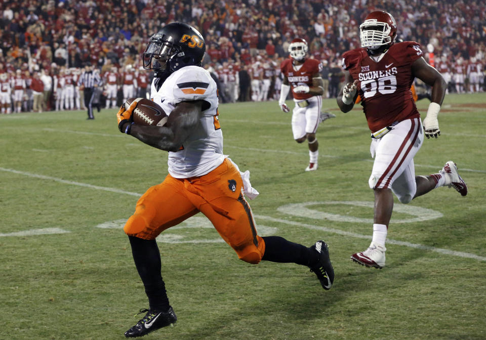 FILE - Oklahoma defensive tackle Chuka Ndulue (98) chases Oklahoma State wide receiver Tyreek Hill, left, who runs a punt return 91 yards for a touchdown in the fourth quarter of an NCAA college football game, tying the score and setting up an overtime, in Norman, Okla., Dec. 6, 2014. (AP Photo/Sue Ogrocki, File)