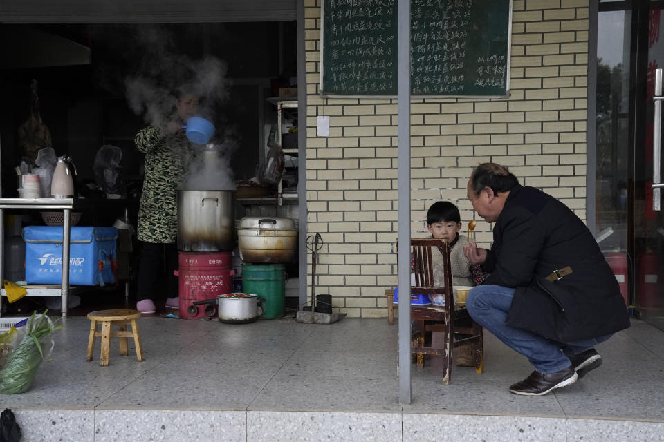 A man and child eat breakfast at a shop across from the Wuhan Jinyintan Hospital where a team from the World Health Organization visited in Wuhan in central China's Hubei province on Saturday, Jan. 30, 2021. (AP Photo/Ng Han Guan)