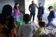 Thuy Do, second from left, and her husband, Jesse Robbins, center, talk with Abdul, second from right, and his family, after they stopped by the vacant rental home they own in Seattle, Monday, Sept. 20, 2021, to drop off produce from their garden and check on the family. Abdul worked as a mechanic before leaving Kabul, Afghanistan about a month ago, and Do and Robbins have provided the house as a place for them live until they can find more permanent housing. Do was nine years old when her family arrived in the United States from Vietnam in the 1980s, and that memory led Do and Robbins to reach out to assist Afghans fleeing their country. (AP Photo/Ted S. Warren)