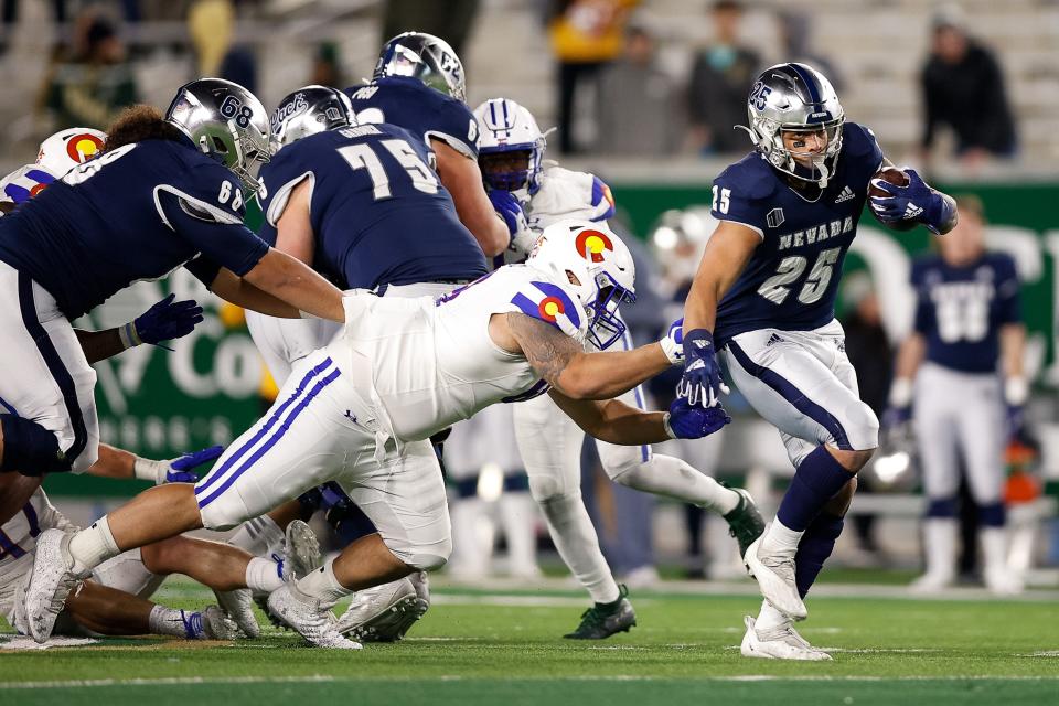 Nevada Wolf Pack running back Avery Morrow (25) passes tackle Colorado State Rams defensive lineman Cameron Bariteau (68) in the fourth quarter at Sonny Lubrick Field at Canvas Stadium on November 27, 2021.