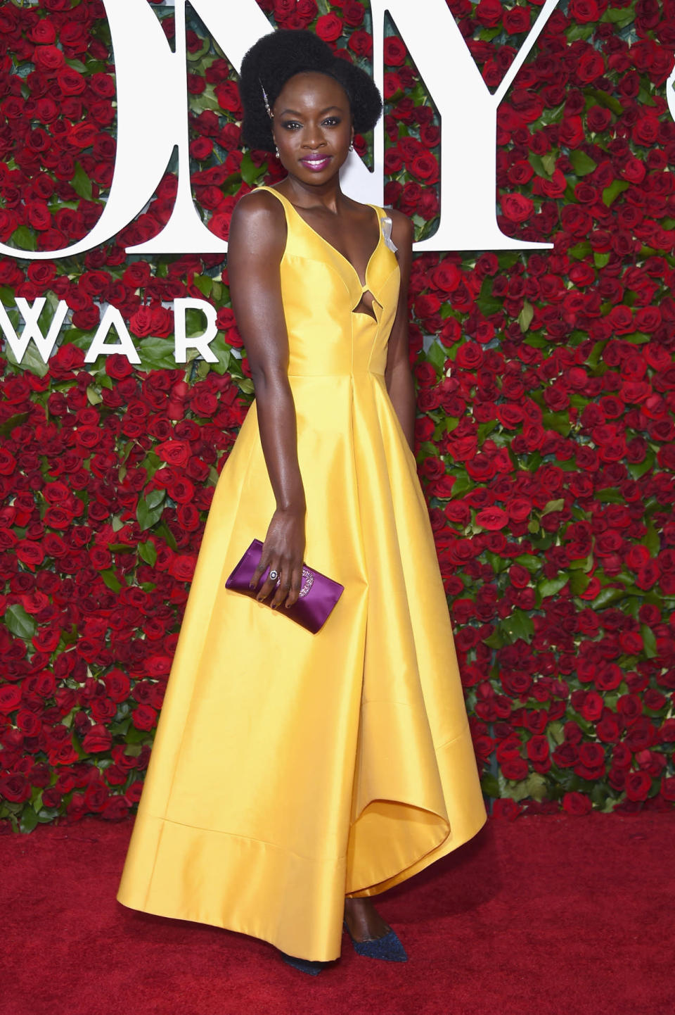 Danai Gurira in a yellow silk dress from Rosie Assoulin with a pink clutch and navy blue heels