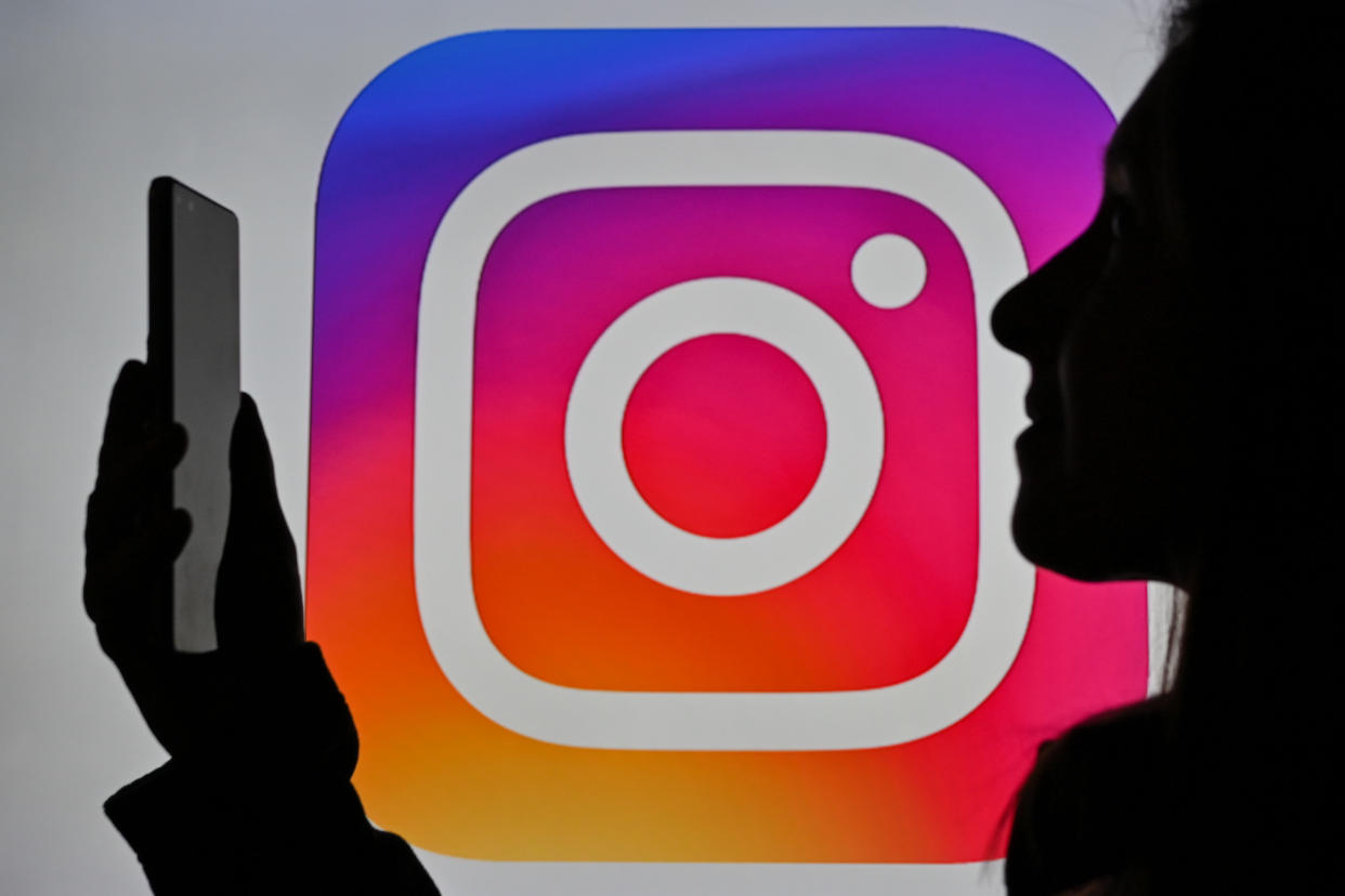 Silhouette of a woman holding a cell phone in front of an Instagram logo.