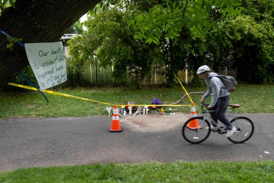 A cyclist rides Monday, May 1, 2023, past a memorial of flowers marking the location that Karim Abou Najm, a graduating senior at UC Davis, was fatally stabbed Saturday in Sycamore Park in Davis. It was the city’s second deadly stabbing at a park in three days.