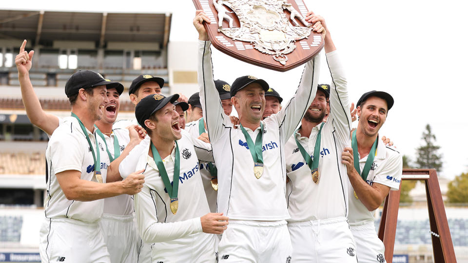 Shaun Marsh holds up the Sheffield Shield trophy flanked by WA teammates.