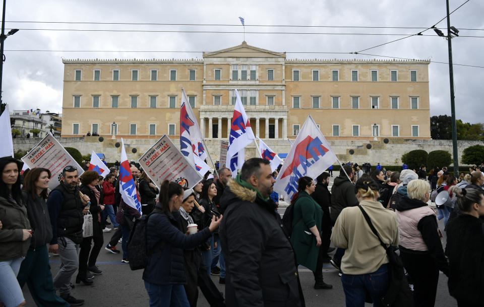 Supporters of the communist party-affiliated PAME, holding placards and flags pass in front of the Greek parliament during a rally in Athens, Greece, Wednesday, Feb. 28, 2024. Widespread strikes in Greece disrupted transport services Wednesday, halting ferries and trains, in protests timed to coincide with the anniversary of a deadly rail crash a year ago. (AP Photo/Michael Varaklas)