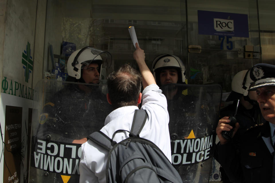 A protester shouts as police protect an open pharmacy during a demonstration in the northern port city of Thessaloniki, Greece, Thursday, March 27, 2014. Greece's pharmacies are closed indefinitely in protest at a recent deal between the Greek government and bailout lenders to deregulate pharmacy store licenses. (AP Photo/Nikolas Giakoumidis)