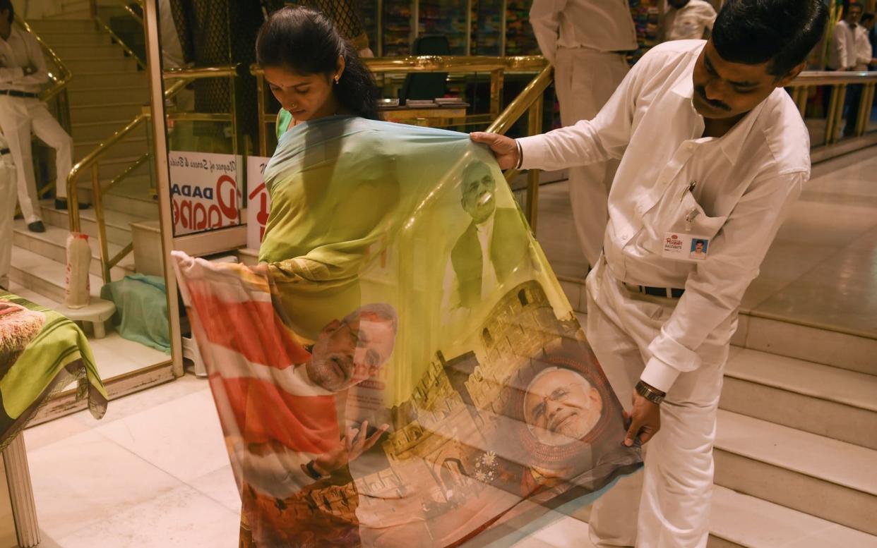 A woman tries on a saree bearing the image of Indian Prime Minister Narendra Modi  - AFP