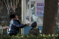 A worker in protective gear collects a sample from a resident at a coronavirus testing site in Beijing, Monday, Dec. 5, 2022. China is easing some of the world's most stringent anti-virus controls and authorities say new variants are weaker. But they have yet to say when they might end a "zero-COVID" strategy that confines millions of people to their homes and set off protests and demands for President Xi Jinping to resign. (AP Photo/Andy Wong)