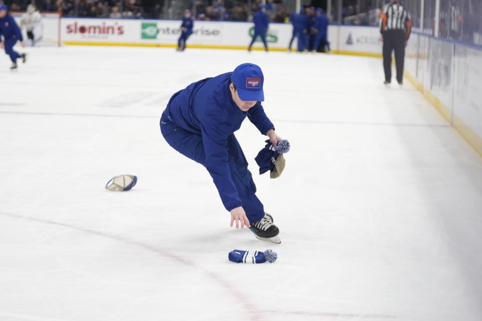 An ice crew member removes hats thrown by fans onto the ice after New York Islanders' Kyle Palmieri scored his third goal in the first period of an NHL hockey game against the Boston Bruins in Elmont, N.Y., Saturday, March 2, 2024. (AP Photo/Peter K. Afriyie)