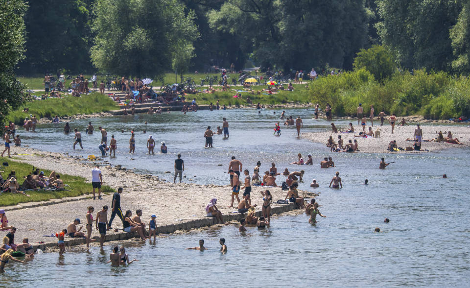 Bathers cool off at and in the Isar River, which flows through the middle of the Bavarian capital of Munich, Germany, Sunday, June 19, 2022. (Peter Kneffel/dpa via AP)