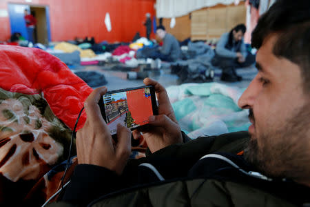 A Kurdish migrant from Irak, plays a war game on his smartphone, as he rests inside a gymnasium in Grande-Synthe, France, January 9, 2019. Picture taken January 9, 2019. REUTERS/Pascal Rossignol