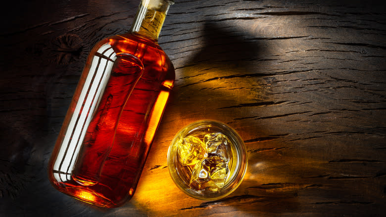 Whiskey bottle on side by glass