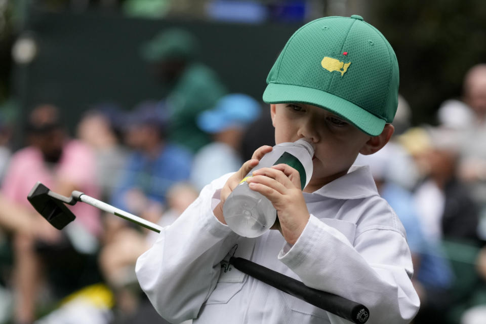 Mackenzie Hughes, of Canada's son Kenton drinks from a water bottle during the Par 3 contest at the Masters golf tournament on Wednesday, April 6, 2022, in Augusta, Ga. (AP Photo/Charlie Riedel)