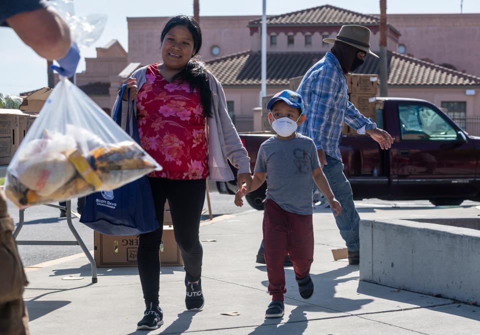 As mother and her son who's wearing a face mask is handed a bag filled with pasta, rice and other essentials during the League of United Latin American Citizens Salinas Council #2055 and United Farm Workers Foundation Food Distribution in Salinas, Calif, on Saturday, May 01, 2020.