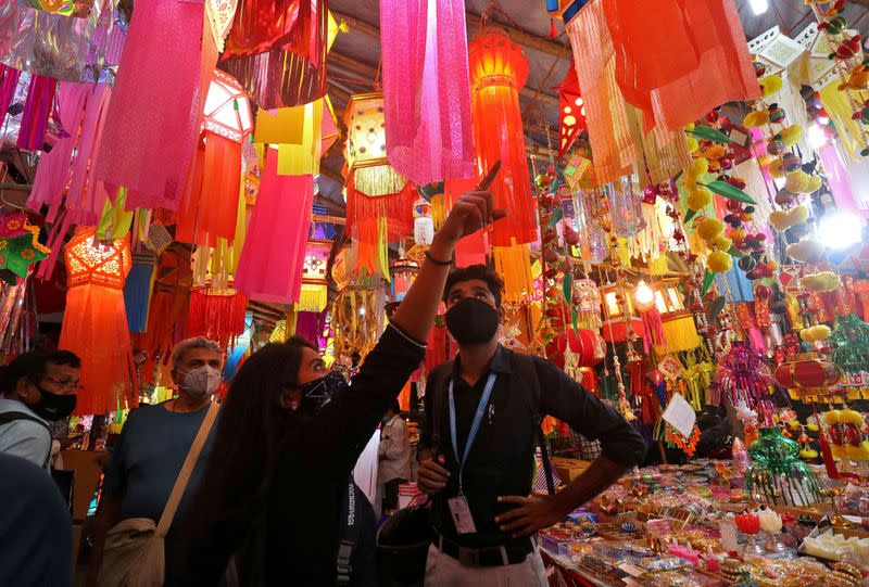 FILE PHOTO: People wearing face masks shop for lanterns at a market ahead of Diwali, in Mumbai