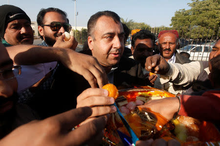 Supporters of Pakistan Tehreek-e-Insaf (PTI) political party, distribute sweets after Pakistan's Supreme Court dismissed a petition to disqualify cricket hero and opposition leader Imran Khan from parliament for not declaring assets, in Karachi, Pakistan December 15, 2017. REUTERS/Akhtar Soomro